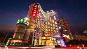 Um hotel com vários andares, fachada iluminada, entrada destacada e design arquitetônico moderno.