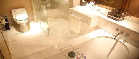 Ein modernes Badezimmer mit einer Glaskabine zur Dusche, einer großen Badewanne und einem Waschtisch mit Spiegel.