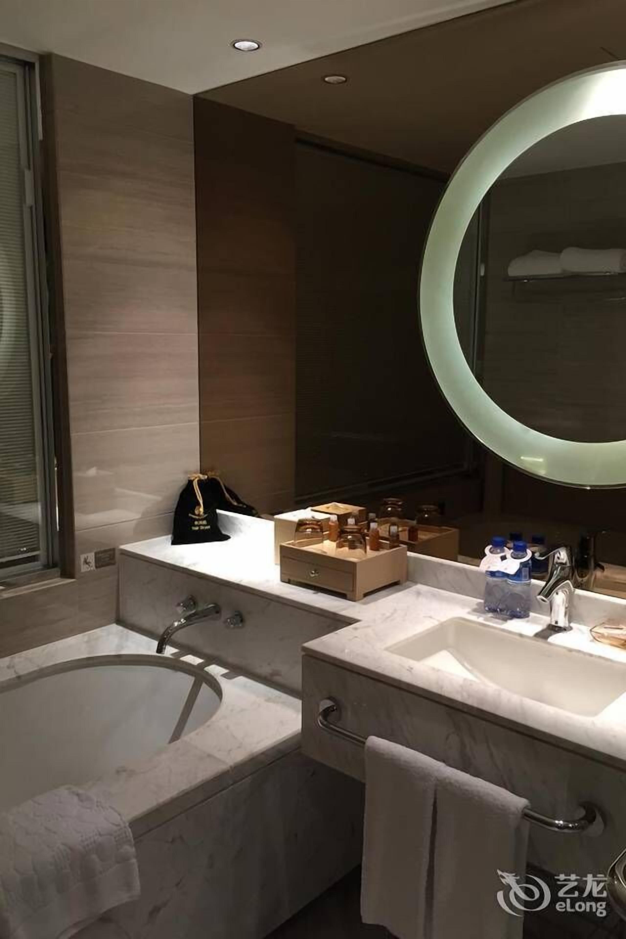 A modern bathroom with a bathtub, a vanity with a mirror, and a towel rack.