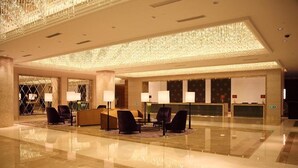 A spacious lobby with a high ceiling, chandeliers, and a reception desk with multiple counters. - Shanghai HongQiao Airport Hotel (Shanghai)