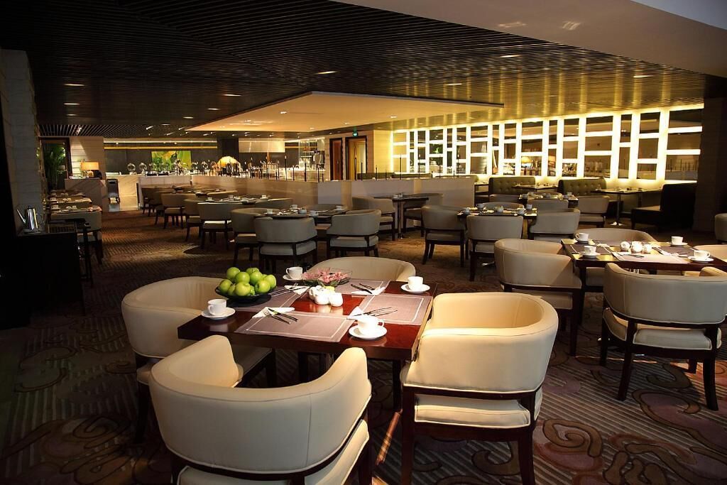 Een ruime eetruimte met meerdere tafels en stoelen, een centraal buffet en een goed verlicht interieur.