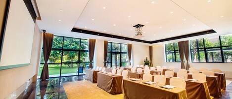 A conference room with tables set for a meeting, large windows with curtains, and a polished floor.
