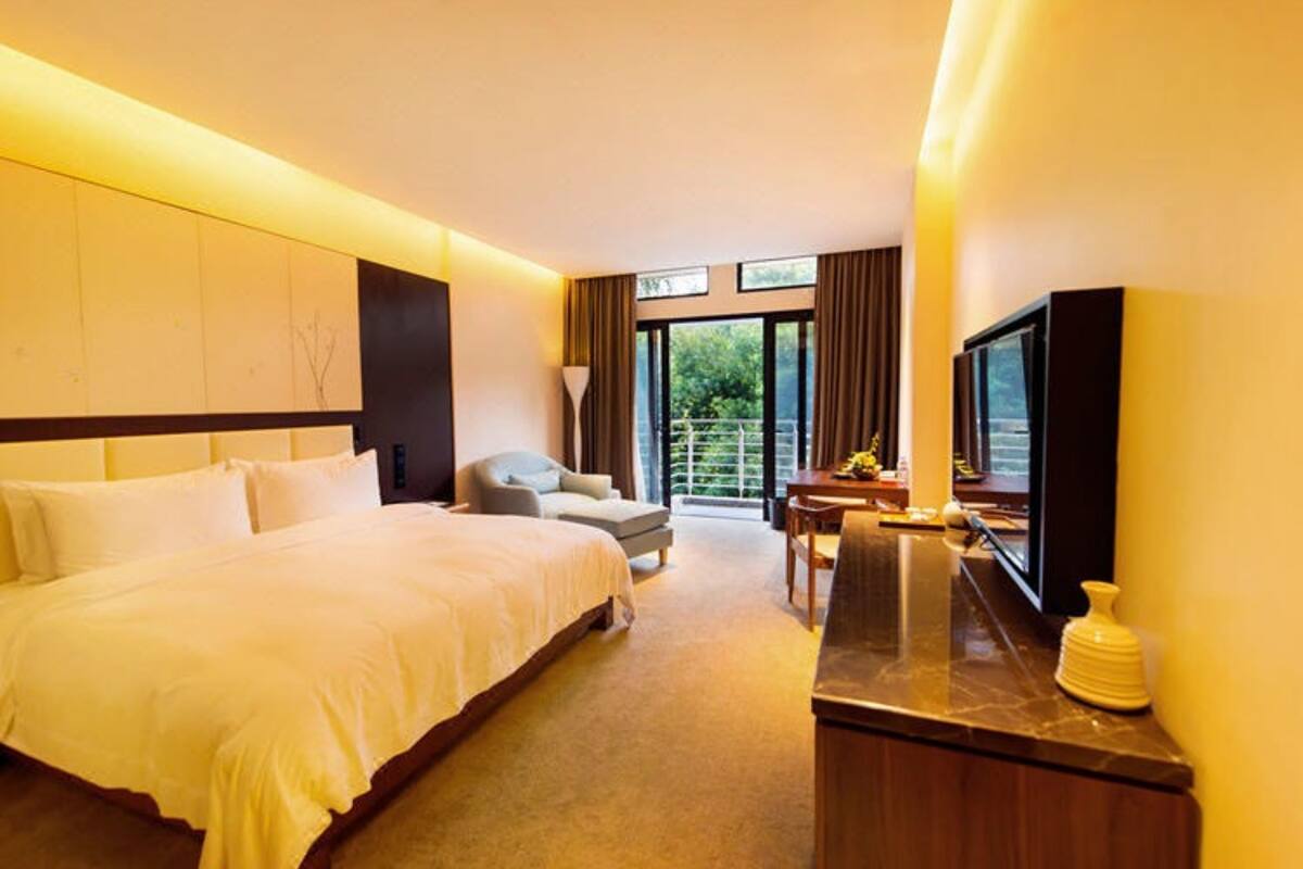 A hotel room with a large bed, a desk, a chair, and a television.