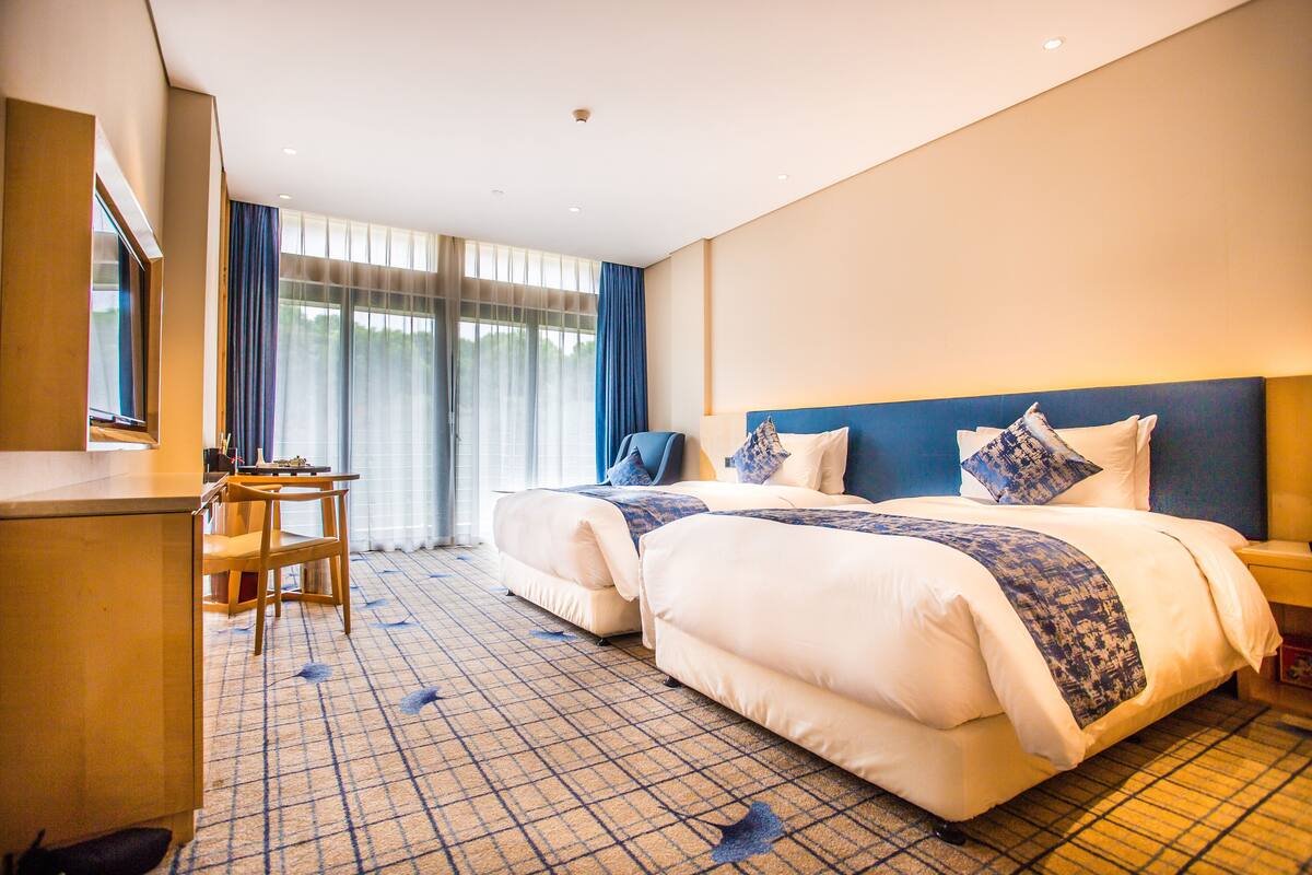 A hotel room with two beds, a desk, and a chair.