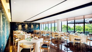 A spacious restaurant with multiple tables and chairs, large windows offering a view of greenery, and a polished marble floor. - Preess Resort Hotel (Changsha)