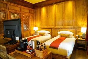 Habitación de hotel con dos camas, paneles de madera, un escritorio con computadora y cafetera.