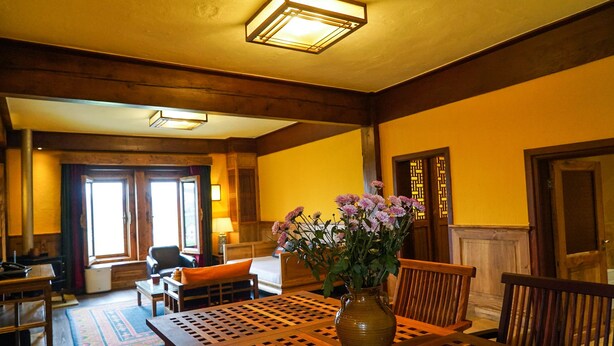 A cozy room with a wooden table, chairs, a vase with flowers, and a fireplace. - Songtsam Linka Shangri-La (Deqin)