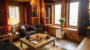 A cozy room with a fireplace, leather armchair, and a table with decorative items. - Songtsam Linka Shangri-La (Deqin)