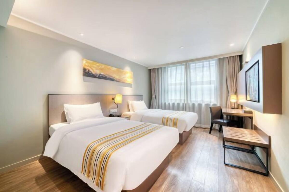 Ein Hotelzimmer mit zwei Betten, einem Schreibtisch und einem Stuhl.