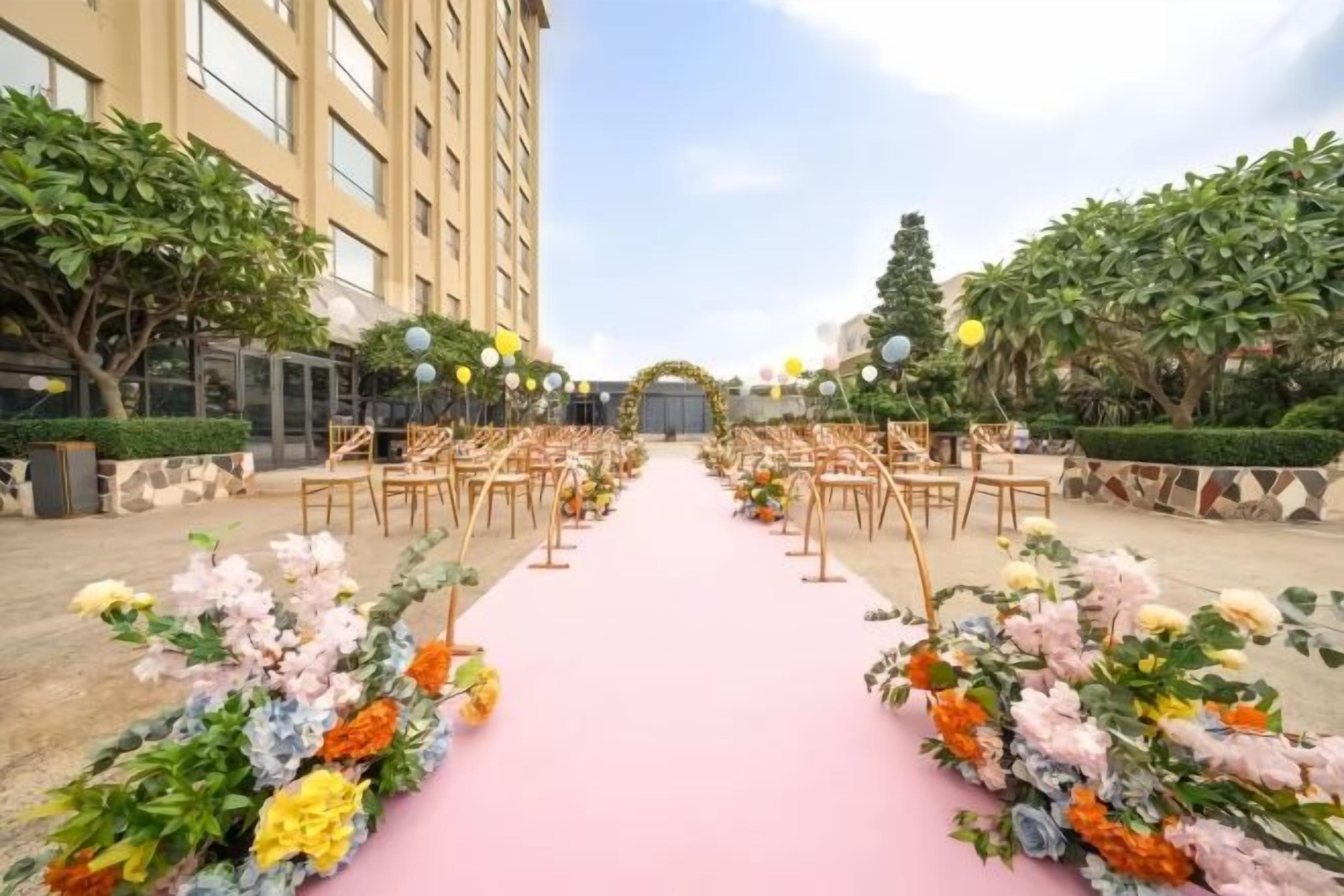 An outdoor wedding aisle with floral arrangements and chairs.