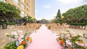 An outdoor wedding aisle with floral arrangements and chairs.