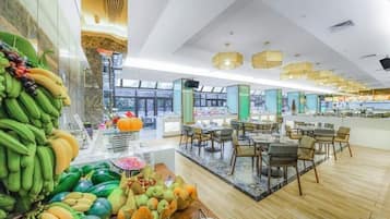 A modern dining area with a central island, seating arrangements, and a variety of fruits displayed on the left.