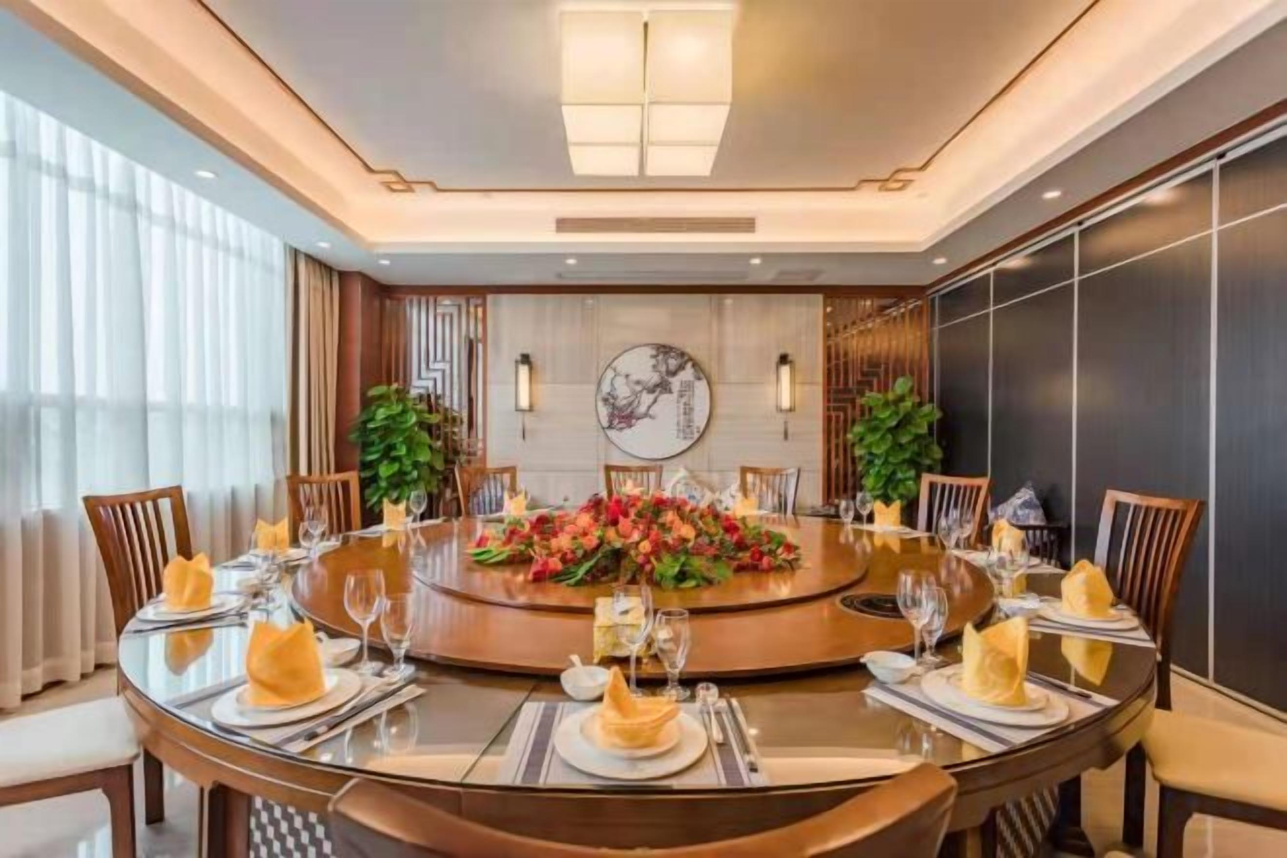 A round dining table with chairs, a floral centerpiece, and a wall-mounted clock.