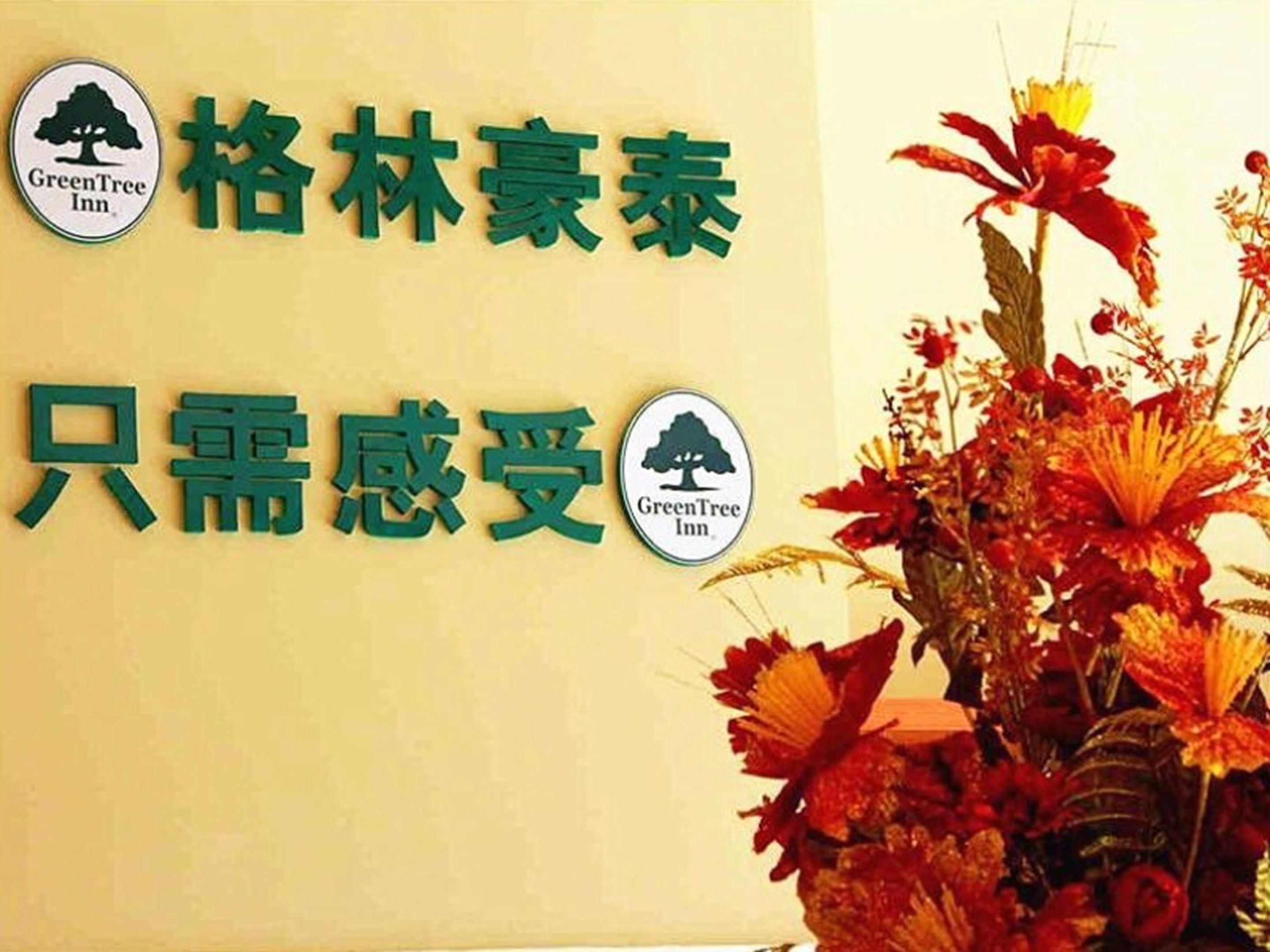 Un letrero de hotel con el logotipo de GreenTree Inn y caracteres chinos.
