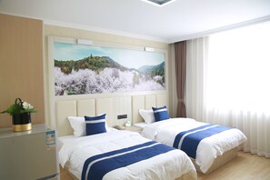 Une chambre d’hôtel avec deux lits, un grand tableau représentant un paysage accroché au mur, une table de chevet avec un téléphone et une fenêtre avec des rideaux.