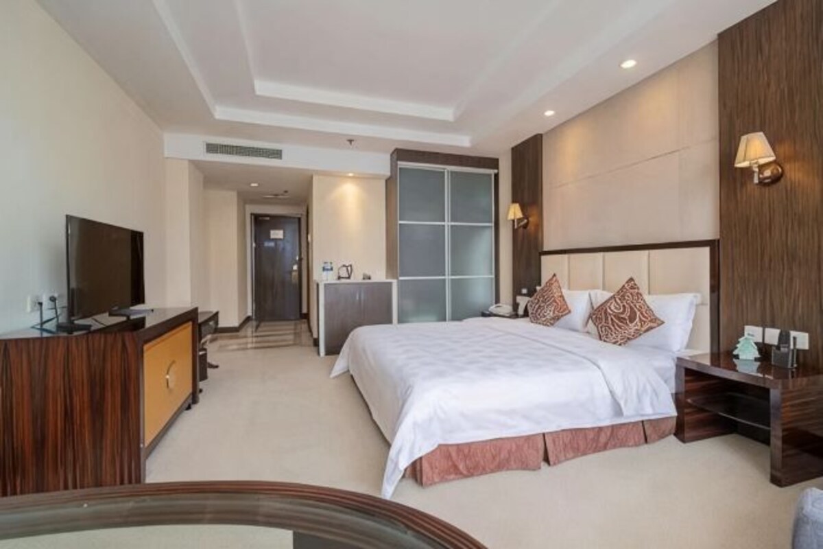 A hotel room with a bed, a TV, a desk, and a bathroom.