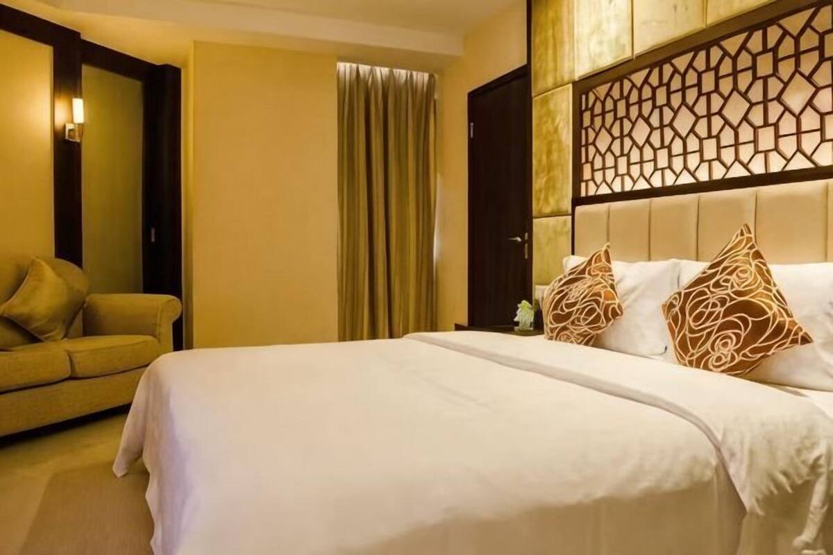 Ein Hotelzimmer mit Bett, einer Couch, einem Vorhang und einer Wandverkleidung.