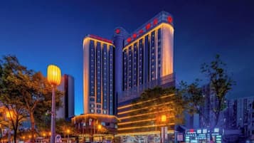 A multi-story hotel with a prominent sign at the top, multiple floors, and a well-lit facade.