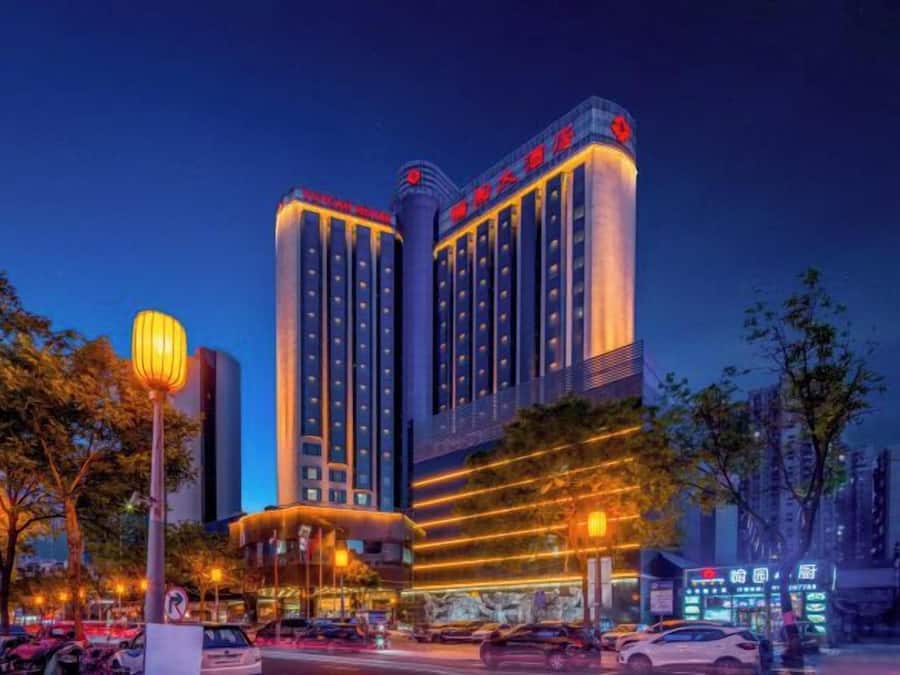 A multi-story hotel with a prominent sign at the top, multiple floors, and a well-lit facade.