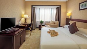 Una habitación de hotel con cama, televisor, escritorio, silla y sofá.