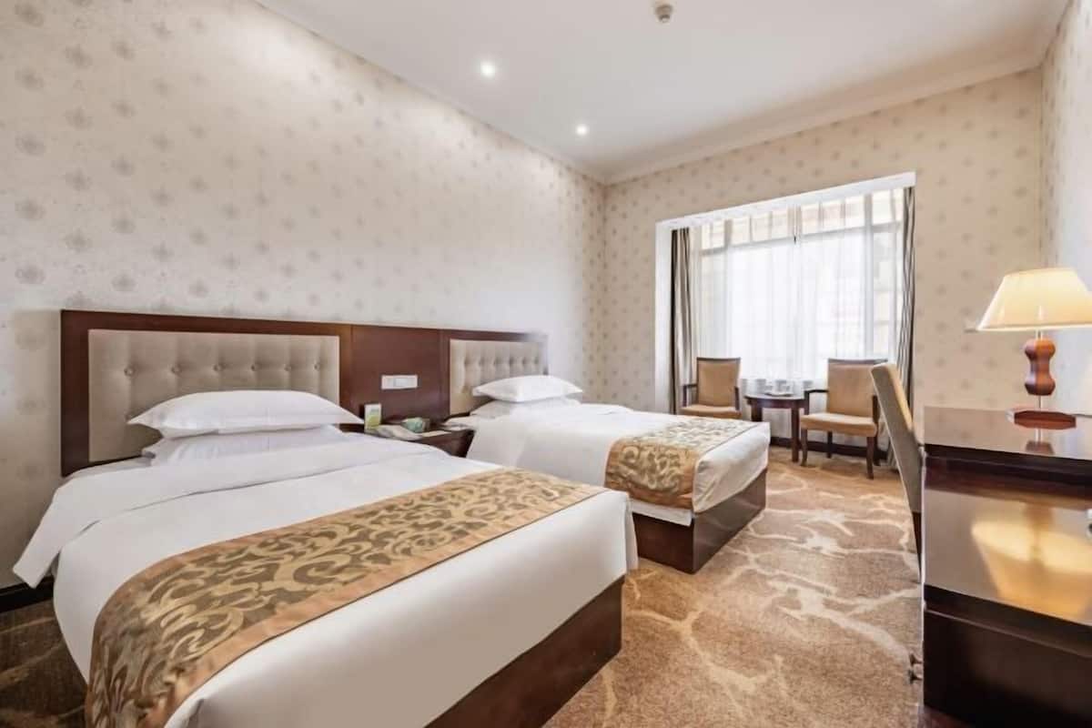 A hotel room with two beds, a desk, and a chair.