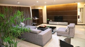 Una sala de estar moderna con un sofá seccional, una mesa de centro, un televisor de pantalla plana y una planta grande.