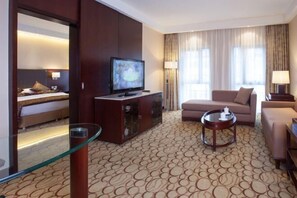 Une chambre d’hôtel équipée d’une télévision, d’un canapé, d’une table basse et d’une cloison en verre.