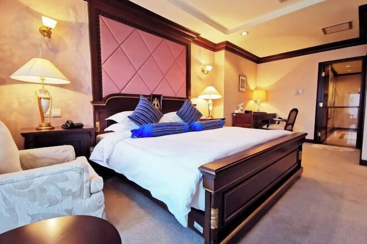 Een hotelkamer met een groot bed, twee nachtkastjes met lampen, een stoel en een bureau met een stoel.