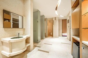 Un baño moderno con un lavabo curvo, un espejo y una zona de ducha.