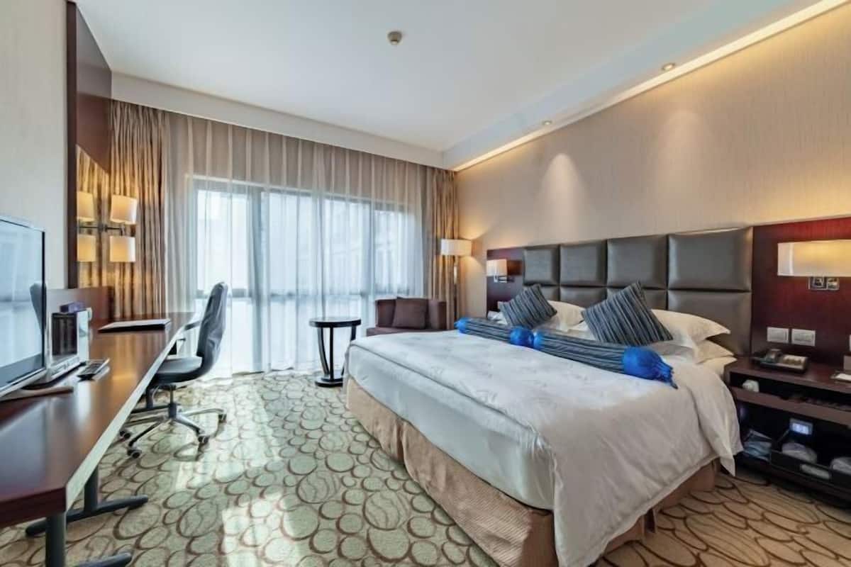 Een hotelkamer met een groot bed, een bureau met een computer, een stoel en een televisie.
