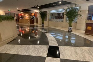 Un hall d’entrée spacieux avec un sol en marbre poli, un comptoir de réception et des plantes en pot.