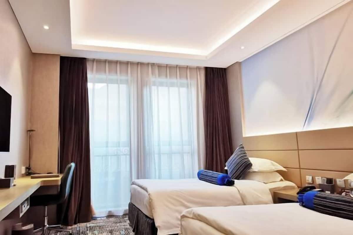 Een hotelkamer met twee bedden, een bureau, een stoel en een televisie.