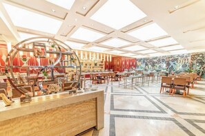 Un vestíbulo de hotel espacioso con techo alto, una recepción central y un muro con diseño.