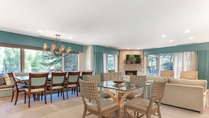 A spacious living room with a glass-top dining table surrounded by chairs, a beige sofa, and a fireplace. - The Galatyn Lodge (Vail)