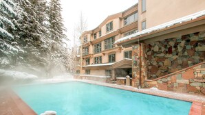A pool area with a stone wall and a wooden deck. - The Galatyn Lodge (Vail)