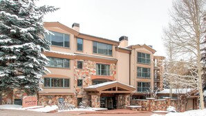 A multi-story building with a stone facade, large windows, and a covered entrance. - The Galatyn Lodge (Vail)