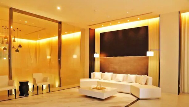Een moderne hotellobby met een witte bank, een bijzettafeltje en een grote wand met donkere panelen.