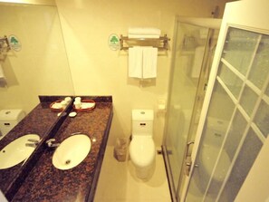 A bathroom with two sinks, a toilet, and a glass-enclosed shower. - Greentree Inn Shantou Haibin Road Chousha Building (Shantou)