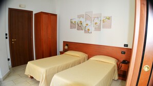 A room with two single beds, wooden wardrobes, a bedside table with a lamp, and wall art. - B&B Centrale (Reggio Calabria)