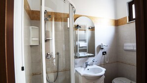 A bathroom with a glass shower enclosure, a sink, a toilet, and a mirror. - B&B Centrale (Reggio Calabria)