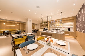 A modern restaurant with wooden paneling, a central island with kitchen appliances, and a variety of seating options including tables and chairs. - Hanting Hotel (GUANGZHOU)