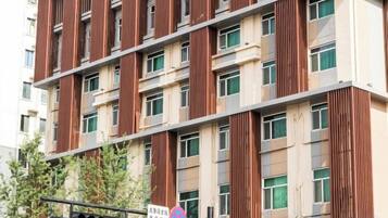A multi-story building with a modern design, featuring vertical wooden slats on the facade and multiple windows per floor.