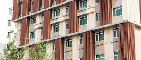 A multi-story building with a modern design, featuring vertical wooden slats on the facade and multiple windows per floor.