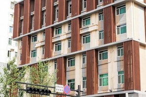 Ein mehrstöckiges Gebäude mit modernem Design, das eine vertikale Holzverschalung an der Fassade und zahlreiche Fenster pro Etage aufweist.