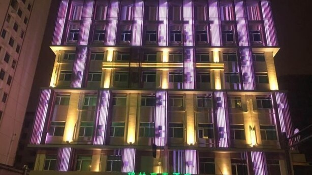 Un hotel de varios pisos con llamativas líneas verticales iluminadas en la fachada.