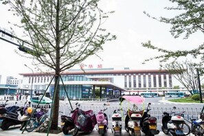 Un espace de stationnement où sont garés plusieurs scooters, avec un arbre au premier plan.