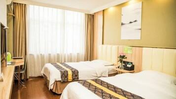 A hotel room with two beds, a desk, and a chair.