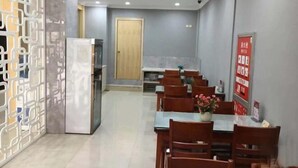 Un comedor con mesas y sillas de madera, un refrigerador y un separador decorativo.