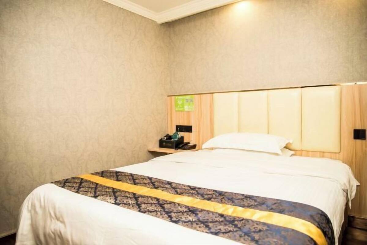 Une chambre d’hôtel avec un lit, une table de chevet et une lampe fixée au mur.