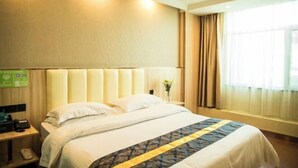 Una habitación de hotel con una cama grande, una mesita de noche con lámpara y una ventana con cortinas.